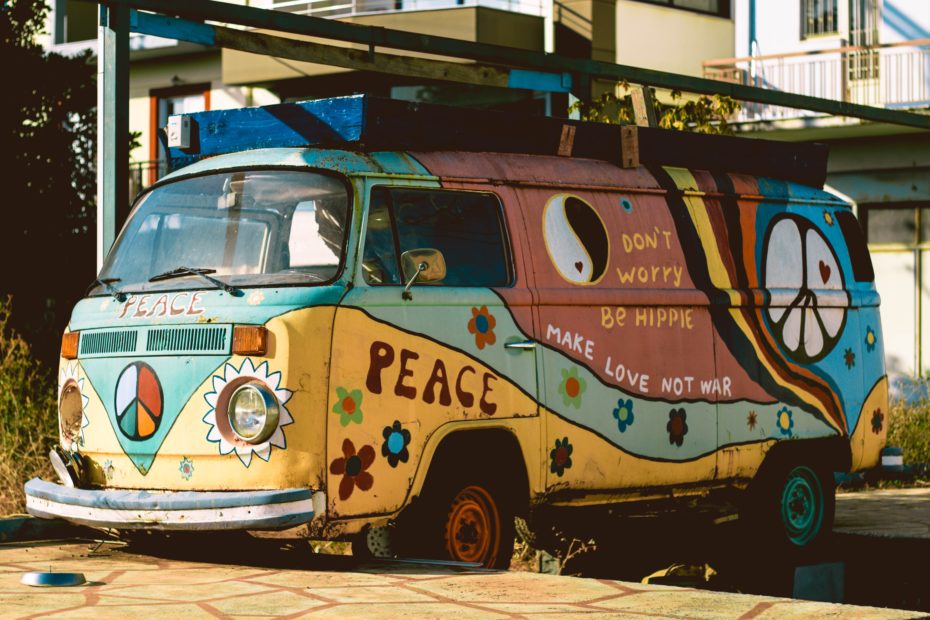 A VW van painted with text like "Peace" and "Don't worry be hippie"